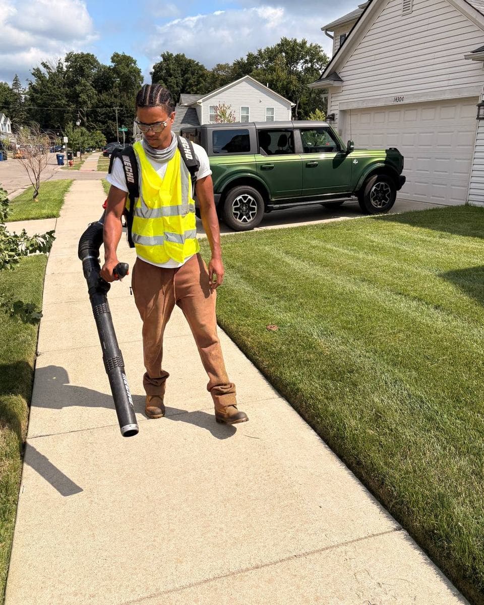 Keonte Woolf, owner of Woolfman Lawn Services, clearing a sidewalk in metro Detroit